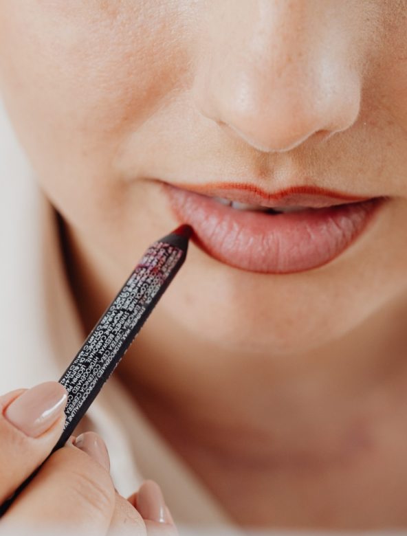 person lining their lip with a lip pencil