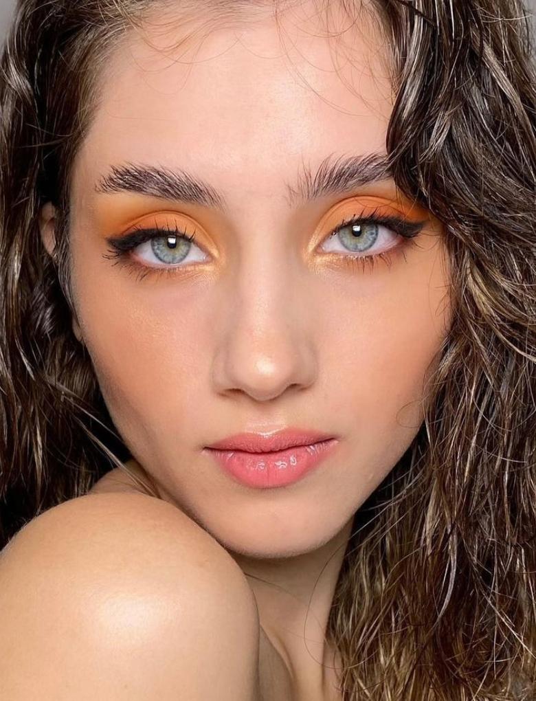 Model with blue eyes wearing orange eyeshadow